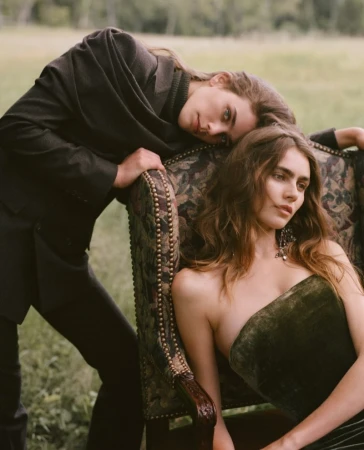Two women posing outdoors with an antique upholstered armchair in a grassy field for the Ralph Lauren Fall 2026 Collection