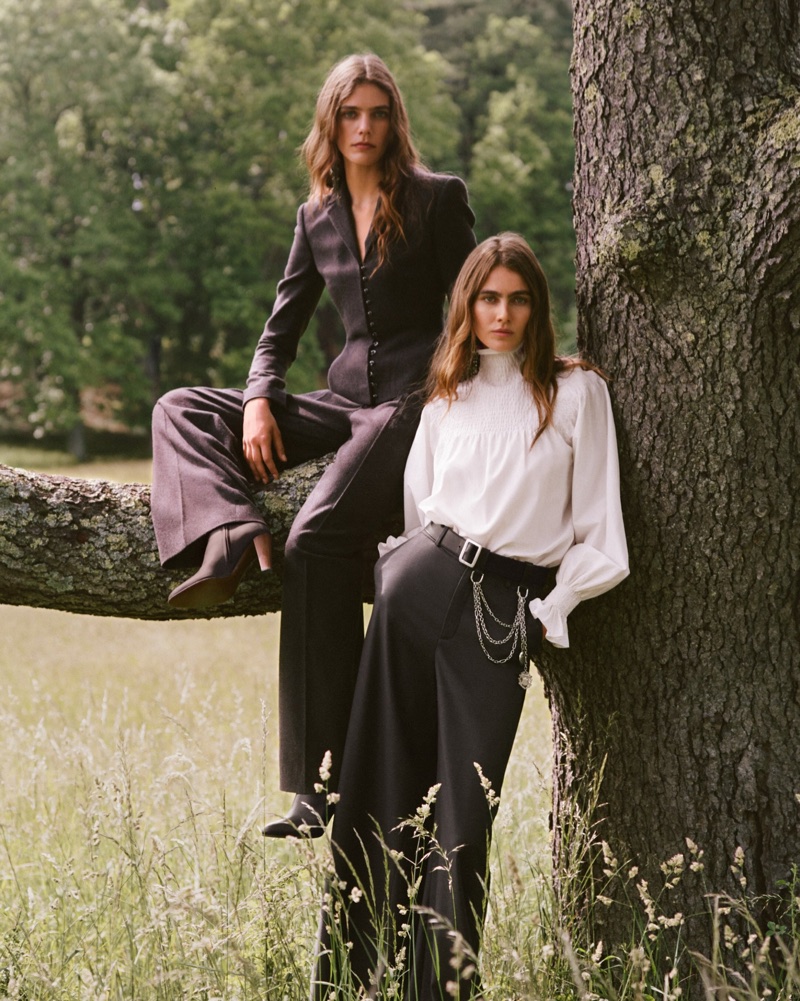 Two female models posing near a large tree in a grassy field, wearing tailored suits and blouses for Ralph Lauren.