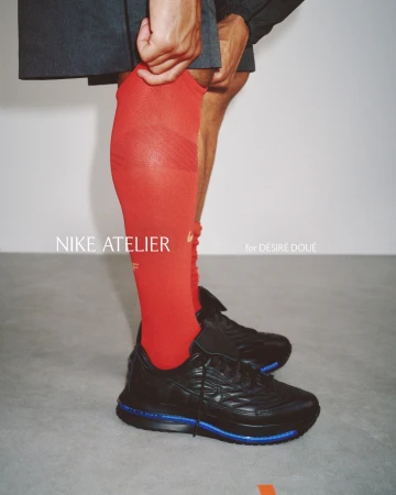Close-up of a person wearing bright red sports socks and black sneakers against a neutral grey studio background