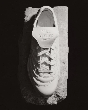 Top-down view of a white leather sneaker resting on a rugged stone slab against a dark background