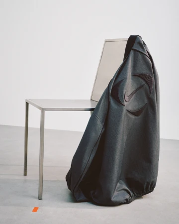 Dark jacket draped over a metallic chair against a minimal white background