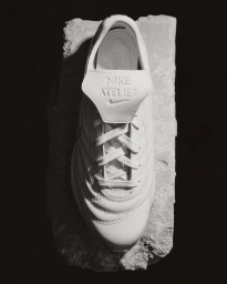 Top-down view of a white leather sneaker resting on a rugged stone slab against a dark background