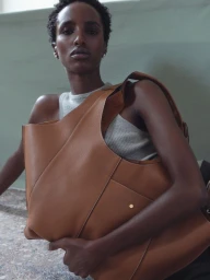 Model Bibi Abdulkadir holding a large brown leather shoulder bag for RSVP Paris, styled by Lorna McGee and photographed by Janne Rugland.