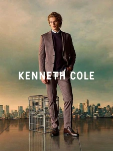 Model wearing a brown suit standing on a rooftop with a city skyline visible in the background for the Kenneth Cole FW 26 campaign