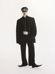 Romeo Beckham wearing an oversized black suit, dark sunglasses, and cap against a plain white background for Document Journal.