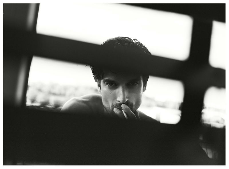 Portrait of a man framed through architectural bars, shot in monochrome for Numero Netherlands Trust project.