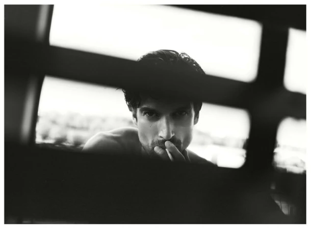 Portrait of a man framed through architectural bars, shot in monochrome for Numero Netherlands Trust project.