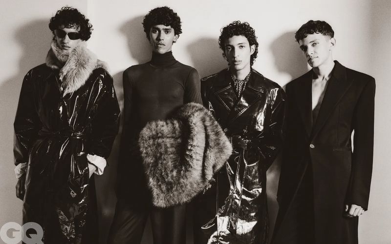 Four male models posing together in Saint Laurent menswear against a plain wall for GQ Middle East editorial photography.