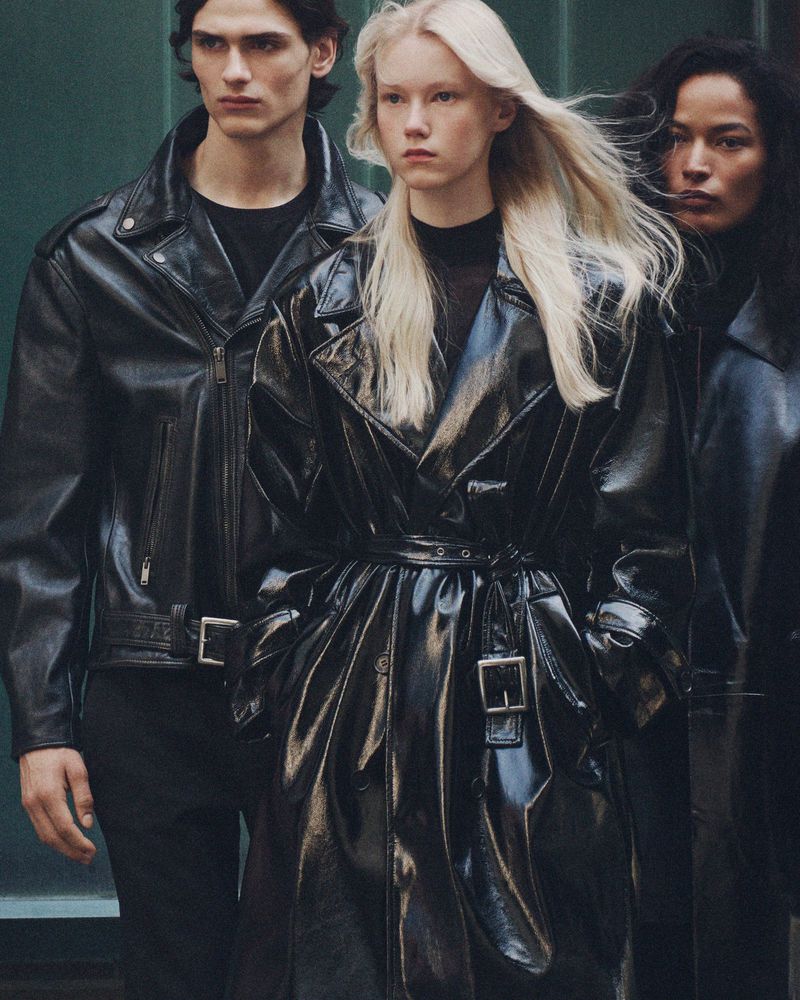 Three models wearing glossy black leather outerwear posing against a green urban background for Zara Pre-owned.