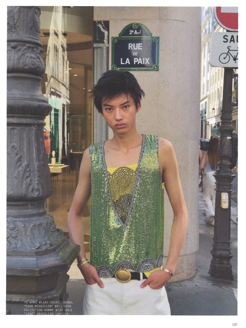 Model wearing a green sequin vest standing on a Paris street near a Rue de la Paix sign for Purple Magazine