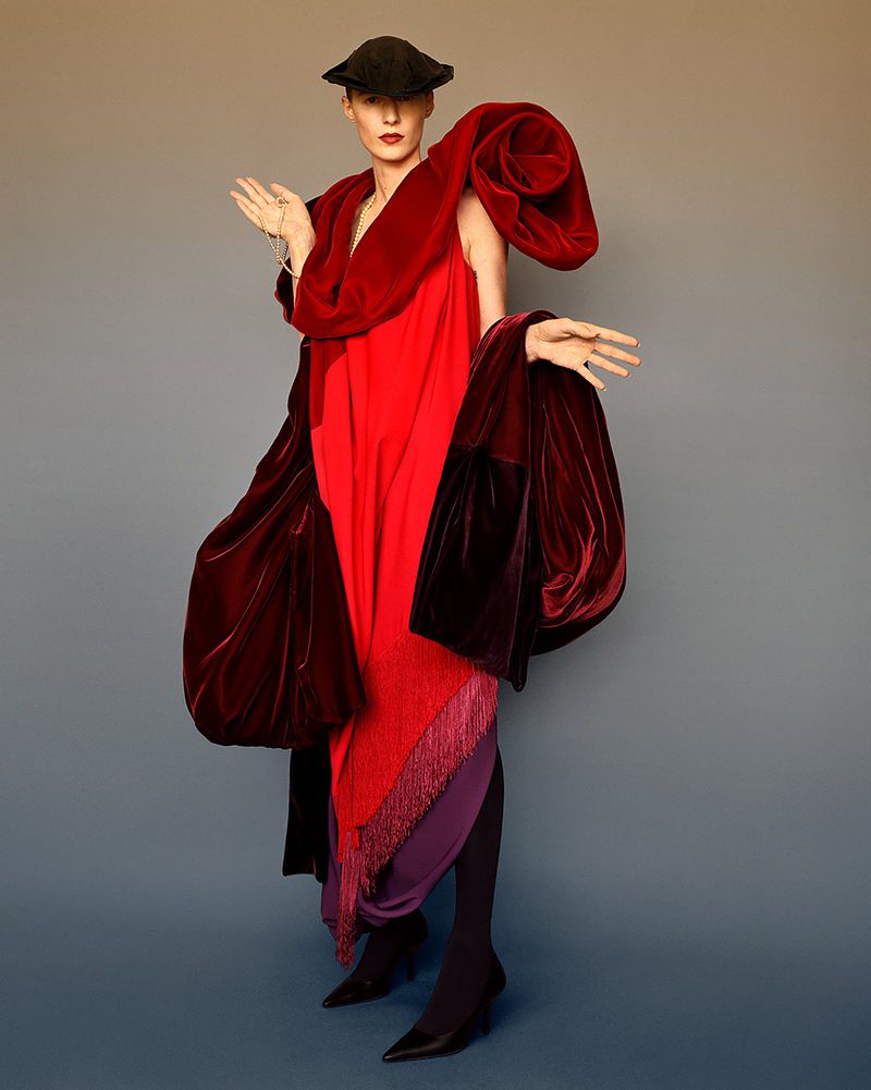 Model Julia Nobis in a vibrant red dress and sculpted velvet wrap against a grey backdrop for W Magazine