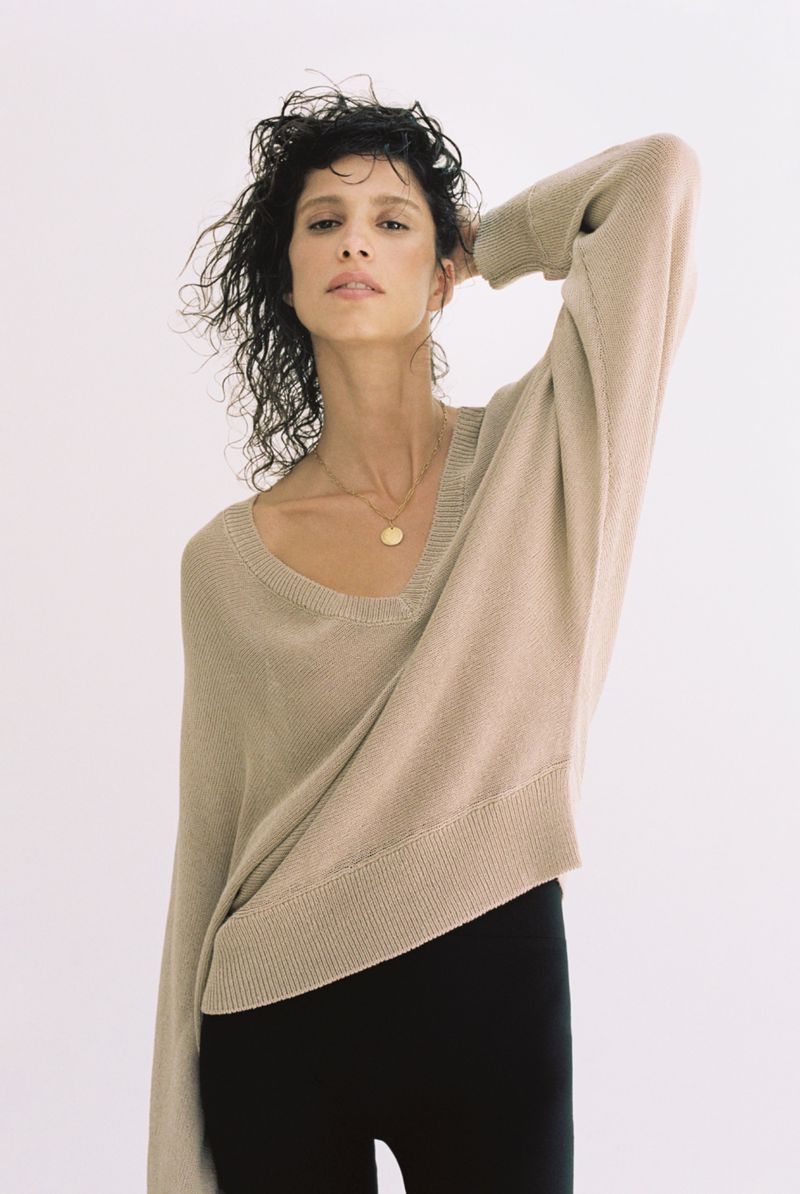 Model Mica Arganaraz wearing a beige knit sweater and black trousers against a white seamless background for Zara