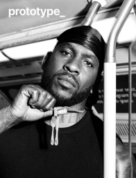 Black man holding a diamond fork and knife pendant necklace wearing a durag and black top on a subway