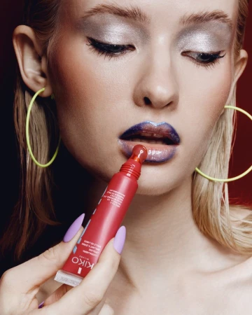Close-up portrait of a model applying red lip gloss wearing neon yellow hoop earrings for KIKO Milano Club K