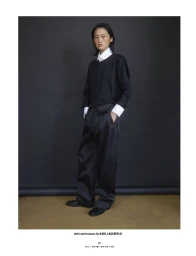 Model in black top and trousers with white shirt collar and cuffs posing against a dark background for 10 Magazine Day Shift