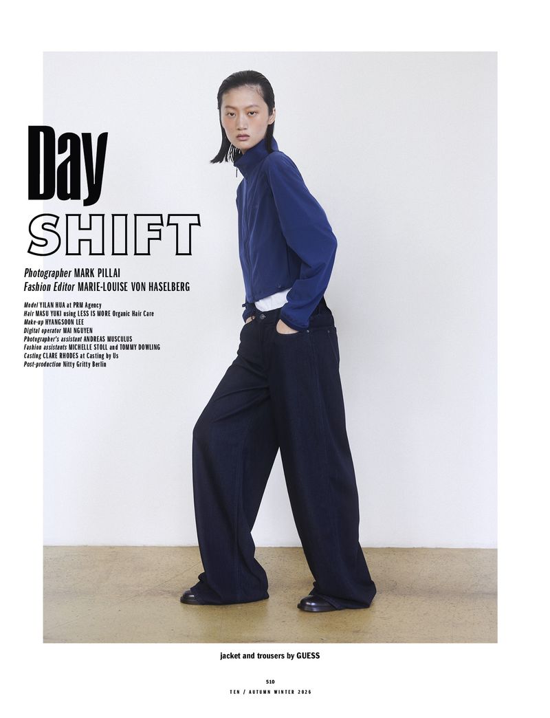 Model Yilan Hua wearing a blue zip jacket and black trousers against a plain wall for 10 Magazine Day Shift editorial