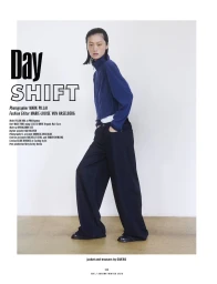 Model Yilan Hua wearing a blue zip jacket and black trousers against a plain wall for 10 Magazine Day Shift editorial