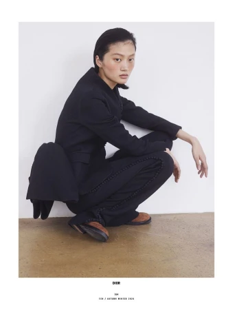 Model Yilan Hua crouching in a black suit against a plain white studio background for 10 Magazine Day Shift editorial.