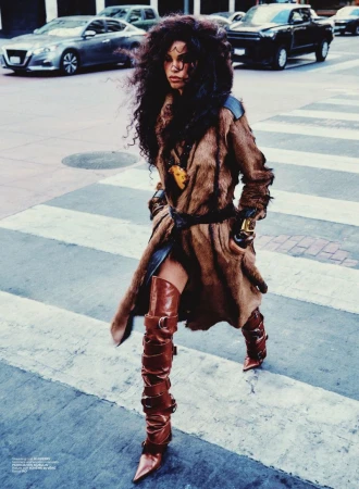 Daiane Sodré walking across a city street wearing a brown fur coat and tall buckled leather boots for V Magazine.