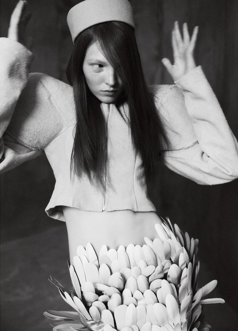 Model wearing a structured jacket, pillbox hat, and petal skirt in a black and white editorial shoot for Elle Hungary.