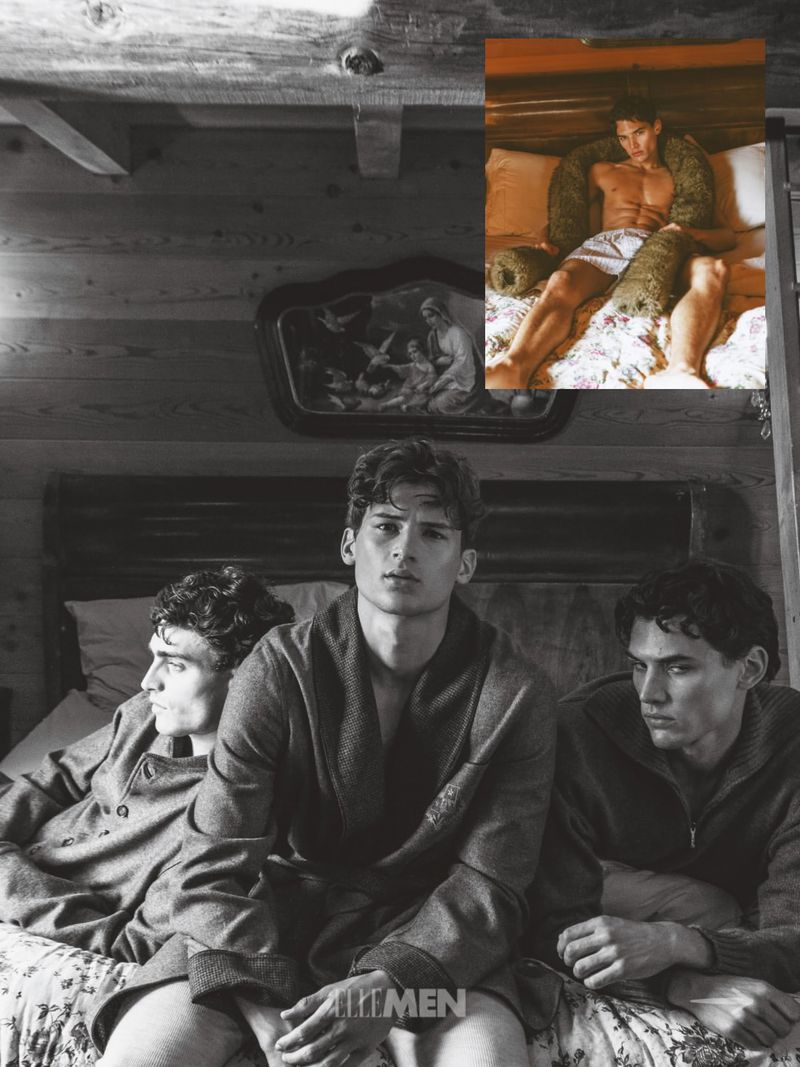 Three male models in robes and knitwear seated on a bed inside a wood paneled room with inset color inset photo above.