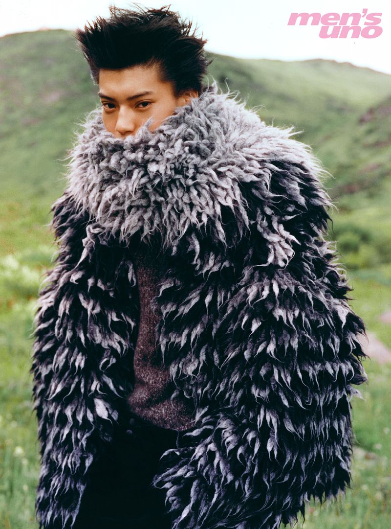 Model Yq in a heavy textured black and grey winter coat standing in a lush green outdoor landscape for Mens Uno China