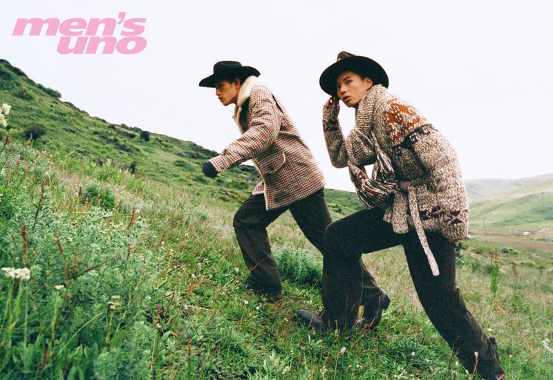 Two male models wearing patterned winter jackets and cowboy hats walking up a grassy hillside for Men's Uno China.