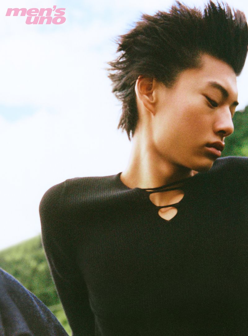 Young man with spiky dark hair wearing a black top against an outdoor green backdrop for Men's Uno China.