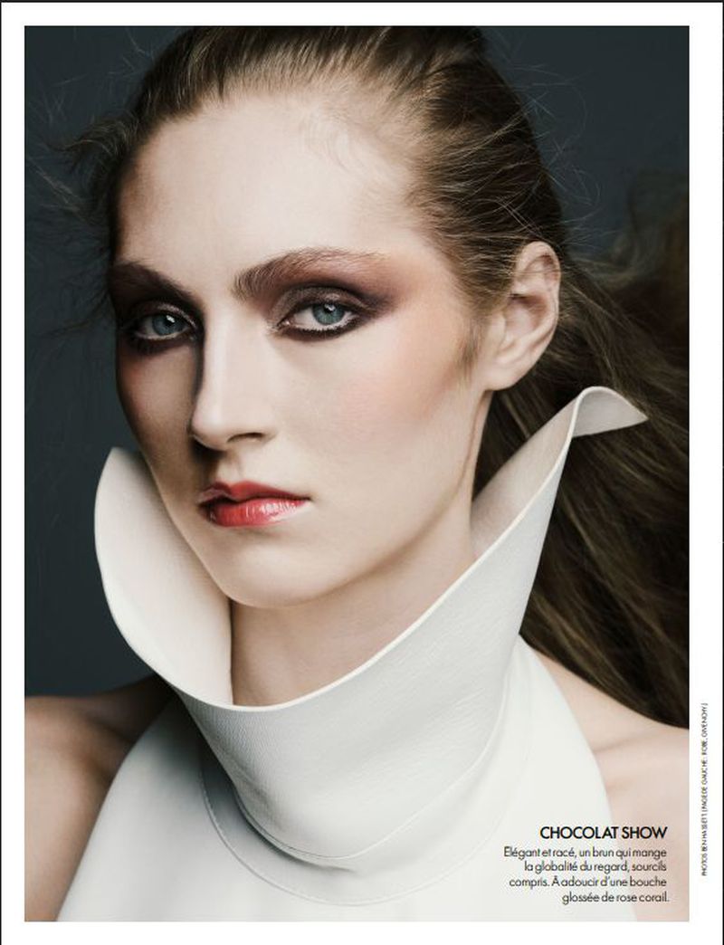 Close-up portrait of a model wearing a structured white high-neck collar with dramatic dark eye makeup for Elle France.