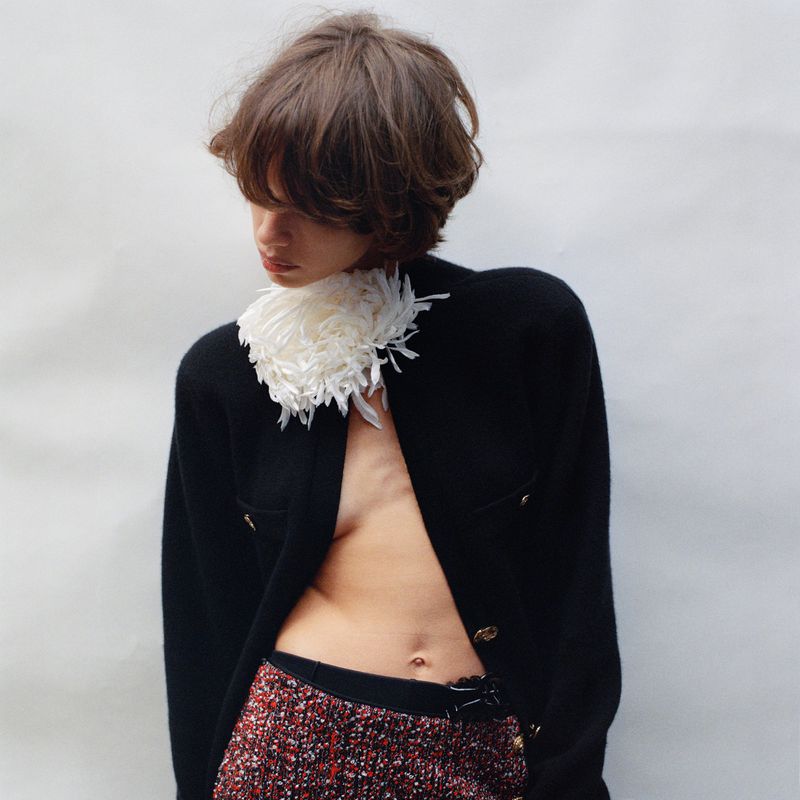 Mathilda Gvarliani in a black cardigan and textured skirt with a white feather collar against a white background for Pop Magazine.