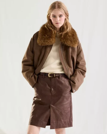 Model wearing a brown jacket with a fur collar and matching skirt against a plain white background.