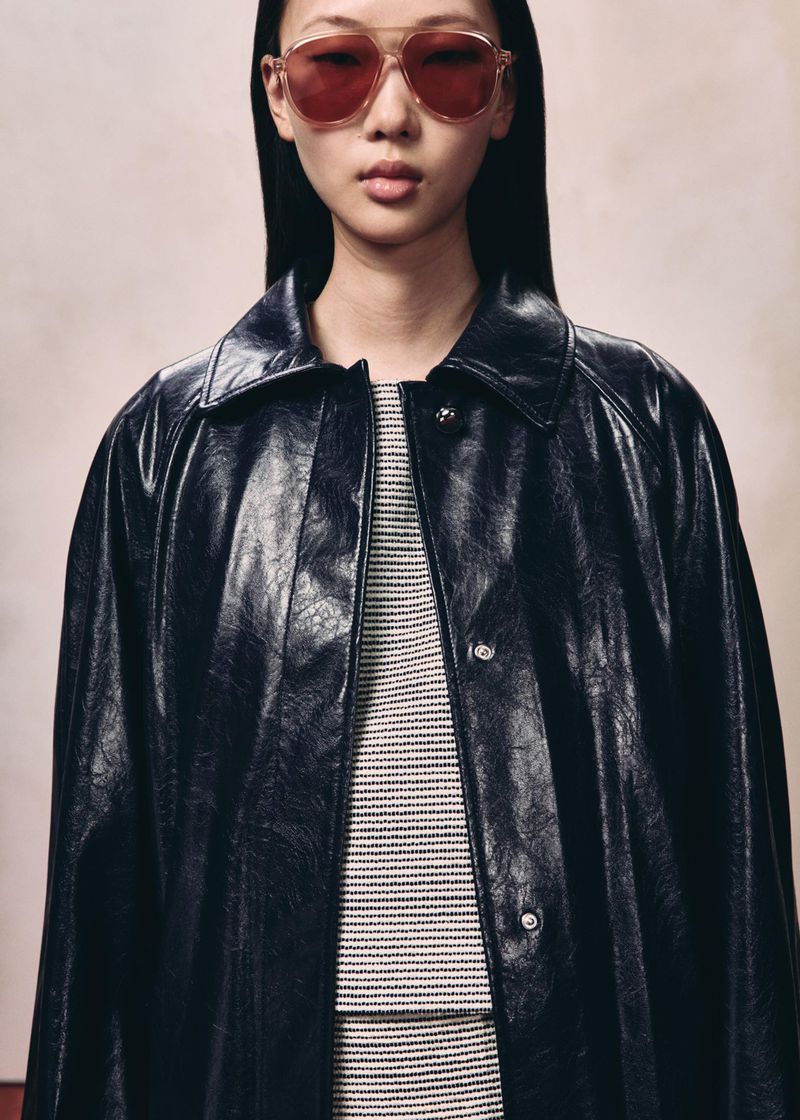 Model wearing tinted aviator sunglasses and a black leather jacket against a neutral studio backdrop