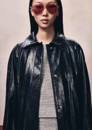 Model wearing tinted aviator sunglasses and a black leather jacket against a neutral studio backdrop
