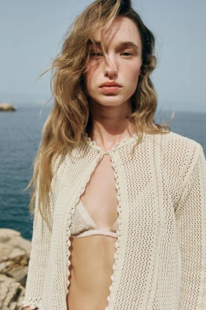 Model Jenn Du Puy wearing a cream knit cardigan against an ocean backdrop in a Zara project photographed by Paolo Steve.