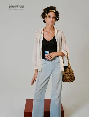 Model Frankie Rayder wearing a sheer white blouse and light blue jeans holding a leopard print handbag against a white backdrop.