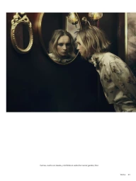 Model looking into a round mirror in a moody interior, wearing a patterned blouse with a bow collar.
