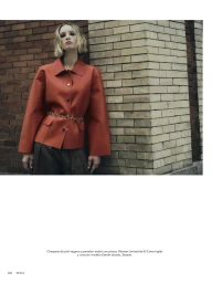 Model leaning against a brick wall wearing an orange jacket and dark trousers for Telva magazine