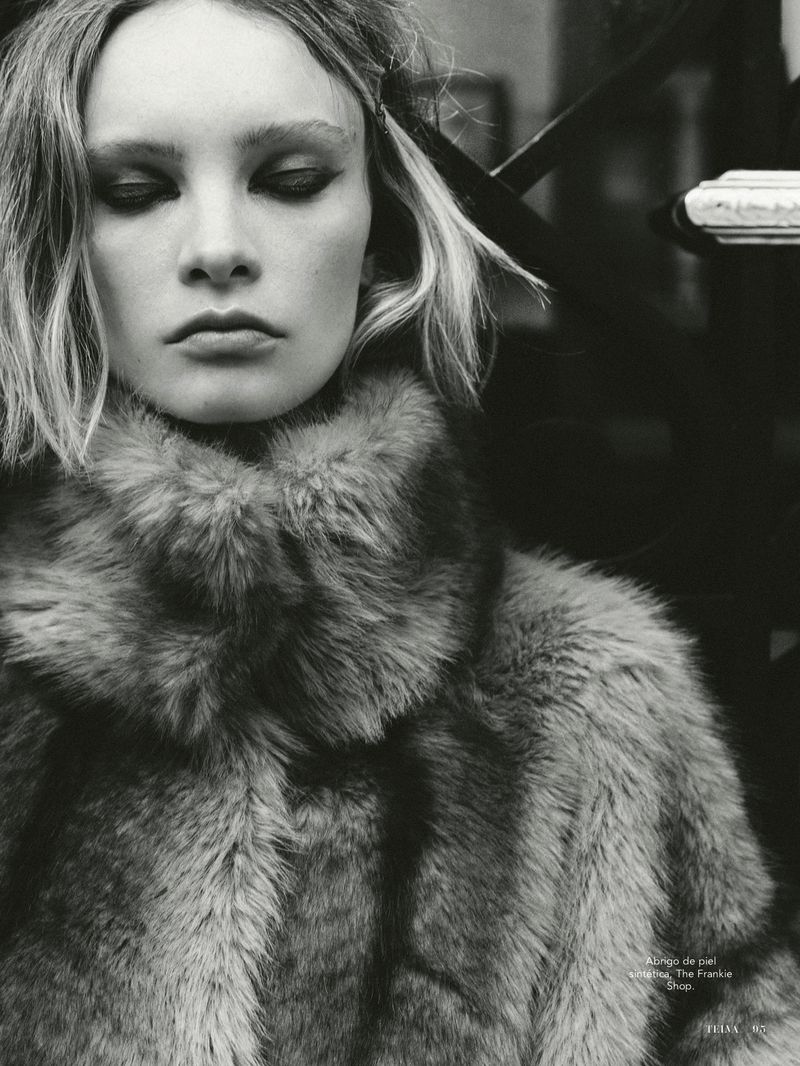 Close-up monochrome portrait of a female model wearing a textured faux fur coat with a high collar.