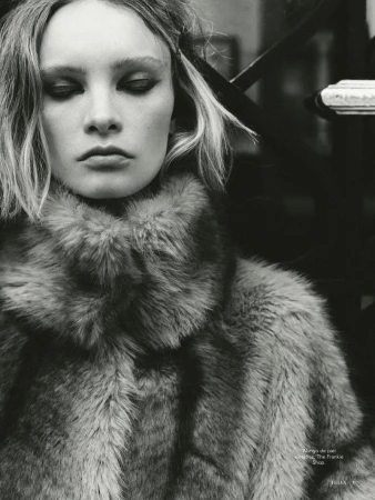 Close-up monochrome portrait of a female model wearing a textured faux fur coat with a high collar.