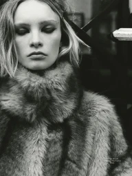 Close-up monochrome portrait of a female model wearing a textured faux fur coat with a high collar.