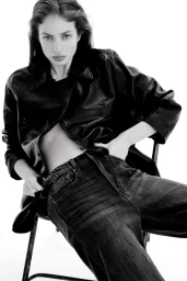 Model Sydney Stabreit wearing a black leather jacket and jeans on a chair against a white background by Olivia Frølich for H&M