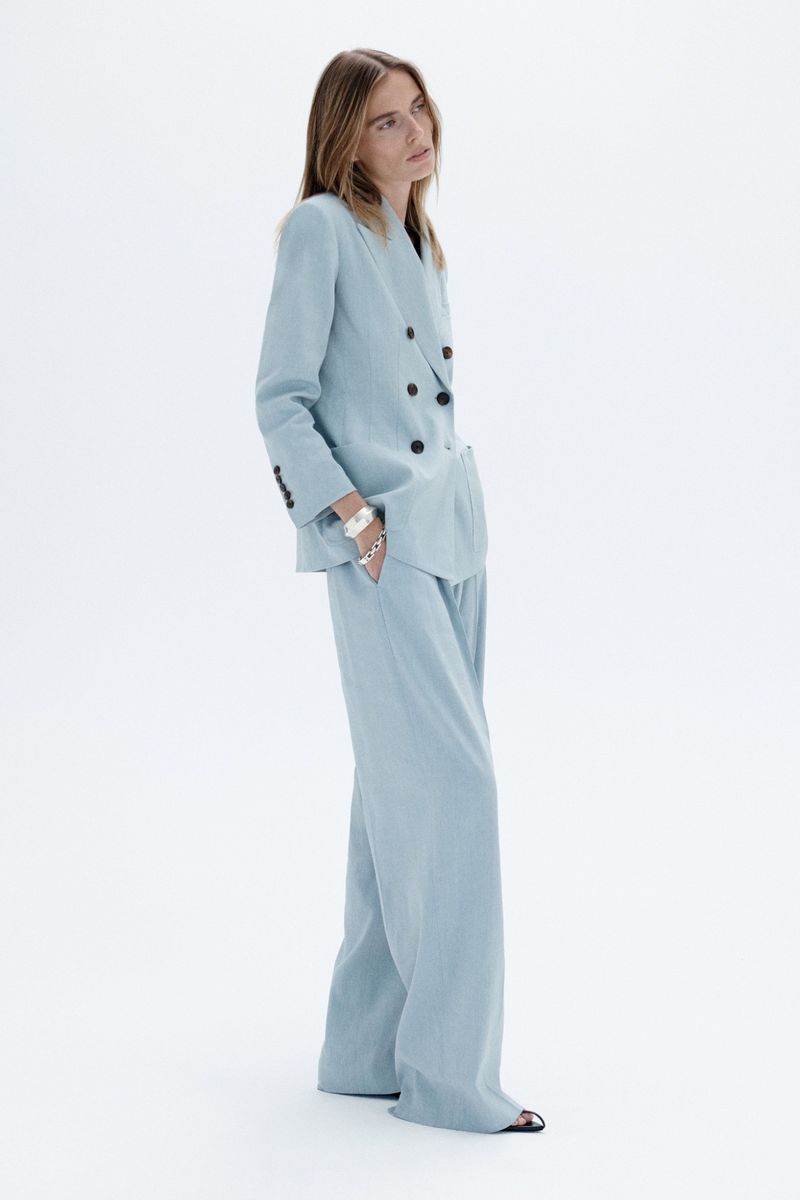 Model wearing a light blue double-breasted suit against a plain white studio background