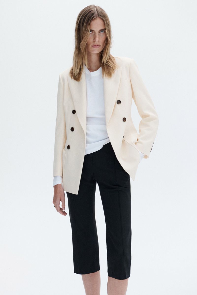 Model wearing a cream double-breasted blazer and black trousers against a white background for A.L.C S/S 27.