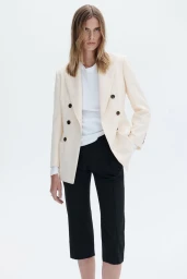 Model wearing a cream double-breasted blazer and black trousers against a white background for A.L.C S/S 27.