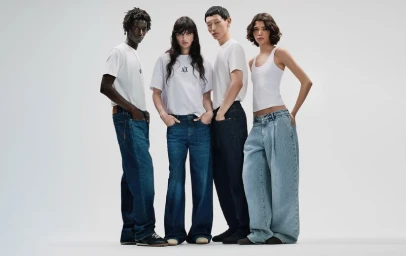 Four models standing against a plain white background wearing white t-shirts and blue denim jeans for Armani Exchange.