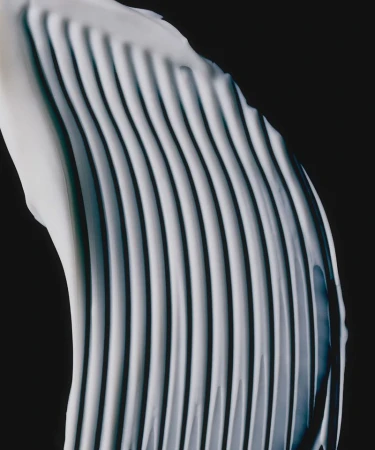 A curved white cream smear showing pronounced parallel ridges against a stark black background.