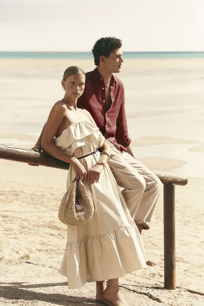 A man and a woman posing outdoors near a sandy beach wearing summer fashion apparel for Pedro del Hierro.