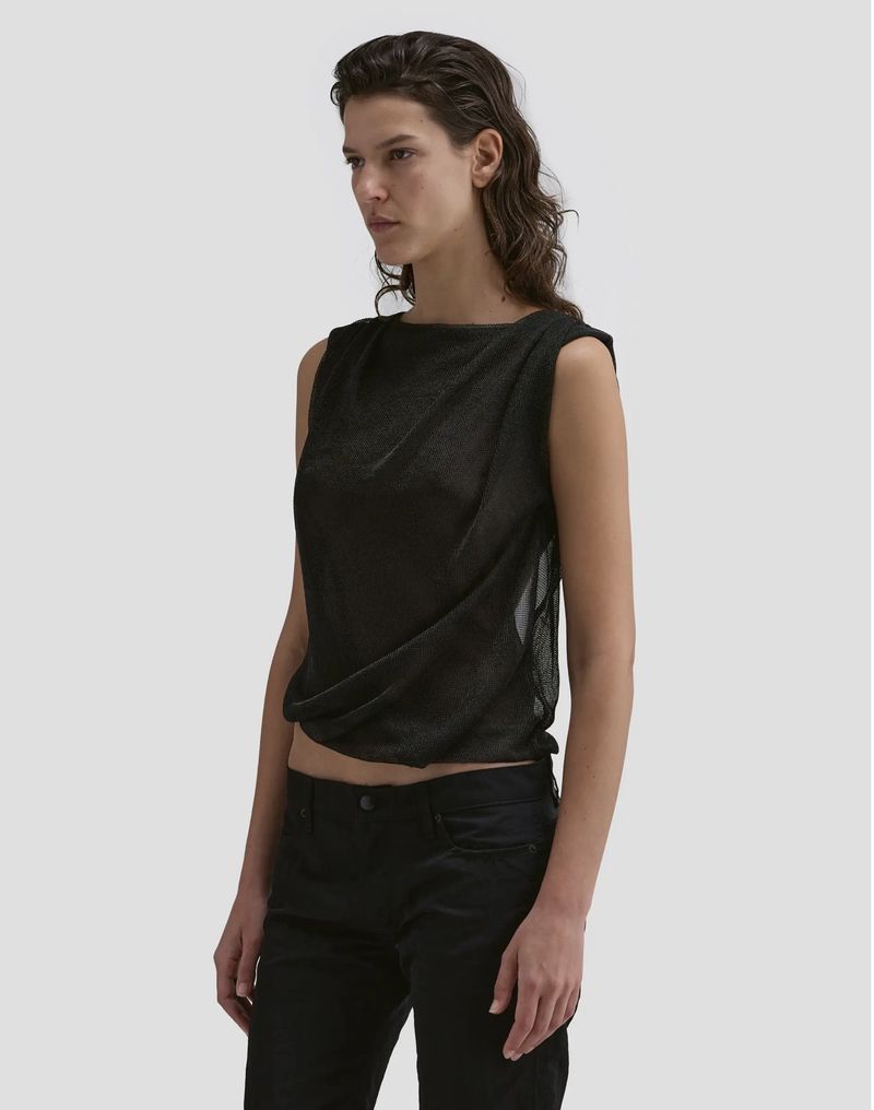 Model Romi Peled wearing a dark sleeveless top and black trousers against a plain white studio background for Eckhaus Latta FW26.
