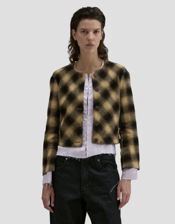 Model Romi Peled wearing a plaid jacket and dark trousers against a neutral background for Eckhaus Latta FW26.