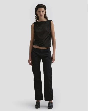 Model Romi Peled wearing a dark sleeveless top and black trousers against a neutral background for Eckhaus Latta FW26.
